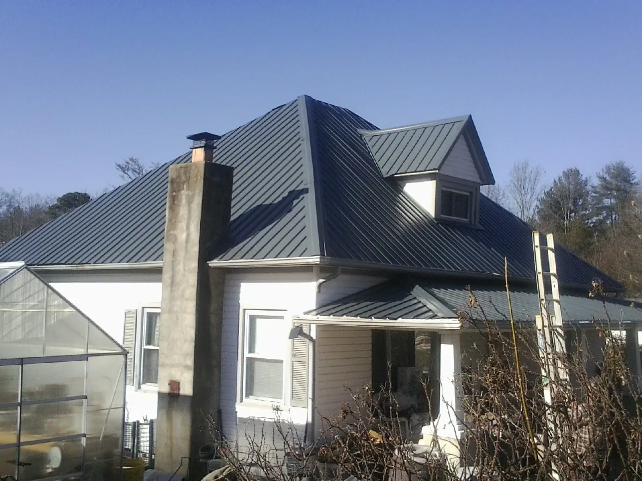Dark blue standing seam metal roof on a white farmhouse with dormer — Slate & Tile Roof Repair by Roofing Brothers in Prospect